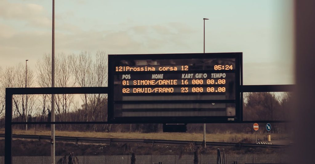 Scoreboard at a motor race track displaying current race information on a cloudy day.